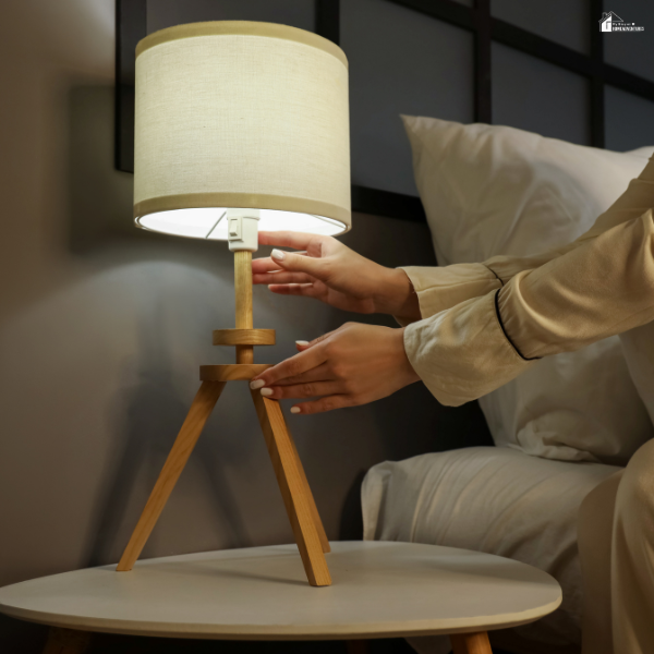 Hand adjusting a bedside lamp, representing small daily tasks that help keep a home functioning smoothly.