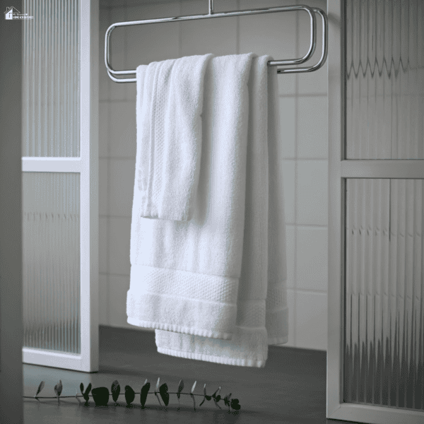 White bath towels hanging on a towel radiator inside a clean, modern bathroom.