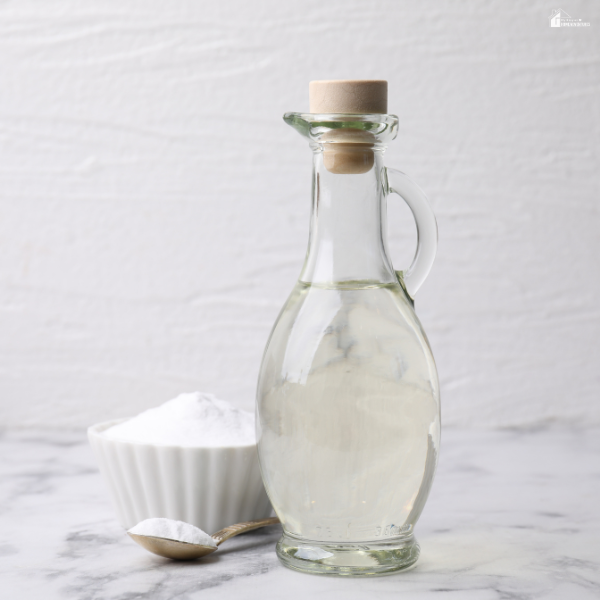Glass bottle with a natural cleaning solution beside baking soda, representing affordable bathroom updates and easy cleaning improvements.