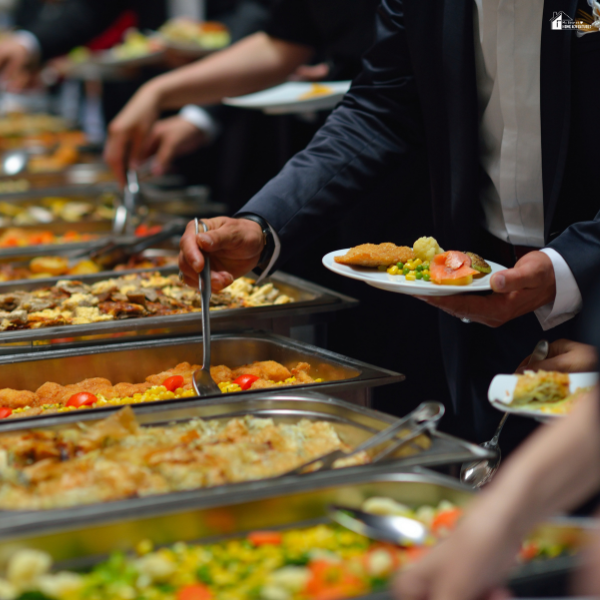 Guests serving themselves from a buffet table with a variety of hot dishes at an Atlanta catering event.