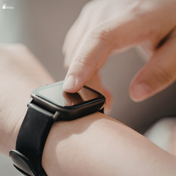Close-up of a hand tapping a smartwatch screen to monitor wearables data during intense workouts.