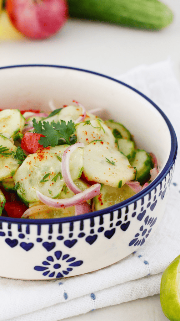 Bowl of Ensalada de Pepino cucumber salad with sliced cucumbers, red onion, tomato, cilantro, and chili seasoning served fresh.
