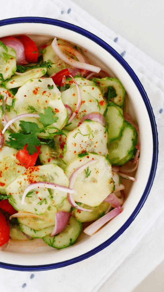 Close-up of Ensalada de Pepino cucumber salad made with crisp cucumbers, tomato pieces, red onion, cilantro, and chili spice.