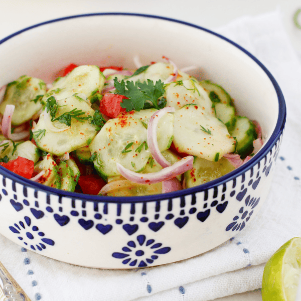 Bowl of Ensalada de Pepino cucumber salad with sliced cucumbers, red onion, tomato, cilantro, and chili seasoning served fresh.