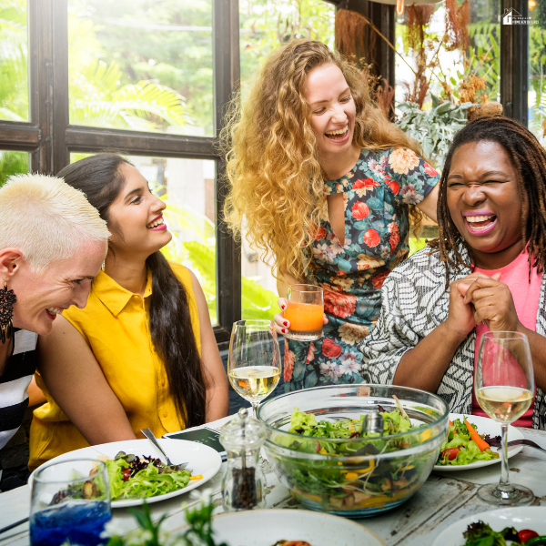 Group of friends laughing around a table with shared dishes, showing affordable ways to feed a crowd while keeping meals enjoyable.