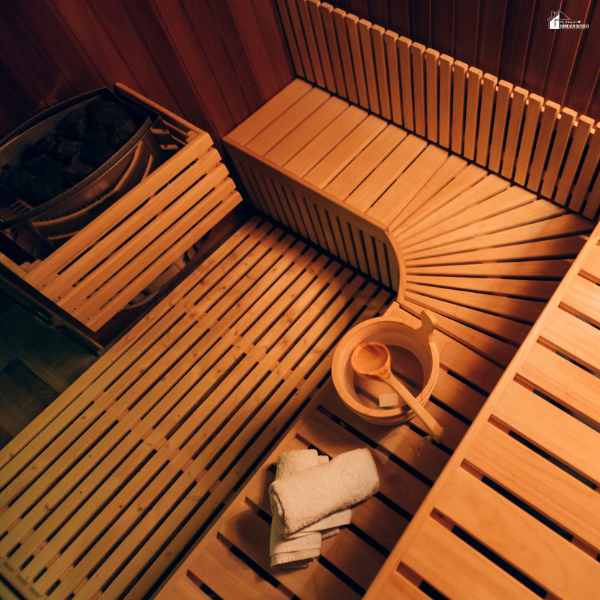 Wooden sauna interior with bench seating, bucket, and towels designed for a calming home wellness experience.
