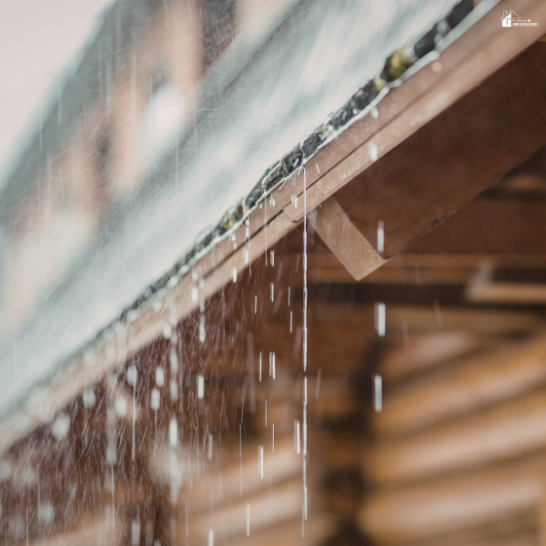Rainwater dripping from a roof gutter during a storm, showing the importance of proper drainage to keep a home dry in rainy weather.