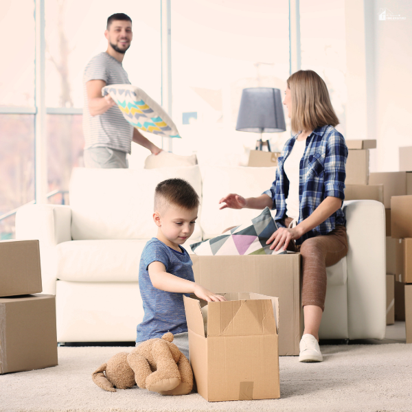 Family packing cardboard boxes in a bright living room while preparing for a budget-friendly long distance move with children.