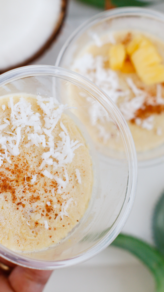 Close-up of creamy Limber de Coco y Piña in clear cups topped with shredded coconut and cinnamon.