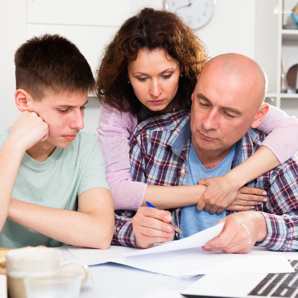 Family reviewing paperwork together at a table, discussing plans and documents to prepare for emergencies and protect their household.