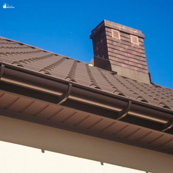 House roof with visible vent near a chimney, illustrating roof ventilation problems that can lead to shingle failure.