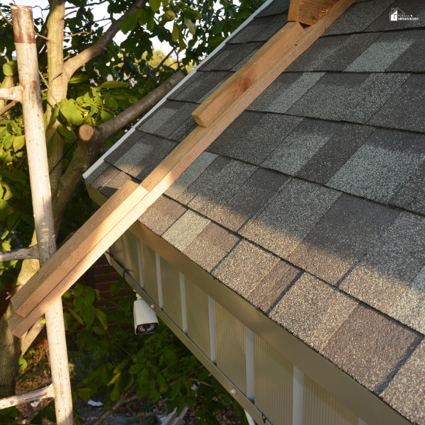 Shingled roof under repair with wooden boards placed across the surface, showing damage linked to poor roof ventilation.