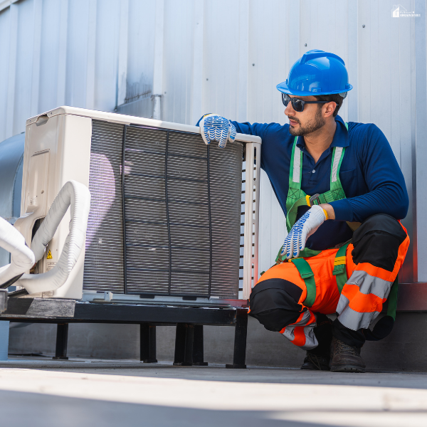 Technician inspecting an outdoor HVAC condenser unit, representing seasonal upkeep to extend system life and avoid breakdowns.