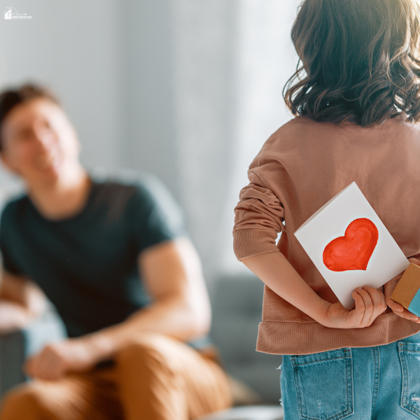 Child holding a handmade card behind their back while approaching a parent, showing thoughtful and easy gift ideas for Father’s Day.