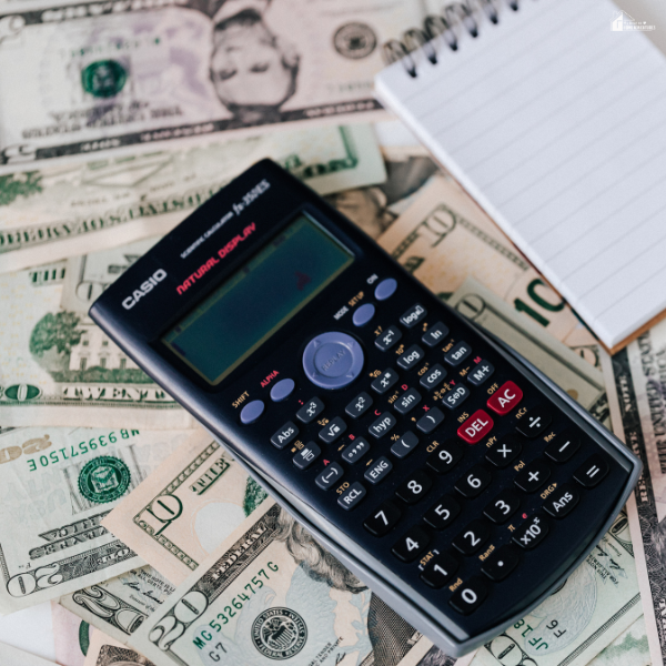 Calculator on cash with notepad representing budgeting habits that help keep finances organized and reduce daily chaos at home.