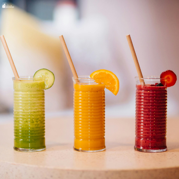 Colorful fruit smoothies in clear glasses with sugared paper straws and fresh garnish, styled for fun drink ideas and party beverages.