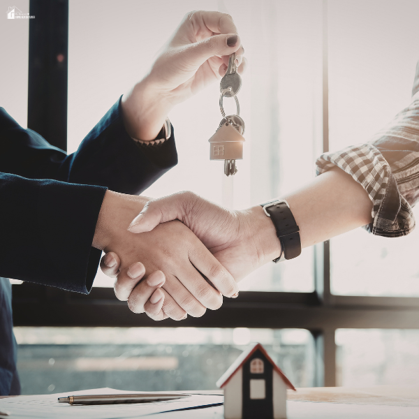 Real estate agent handing house keys to a buyer during a sale that appeals to an upscale home buyer.