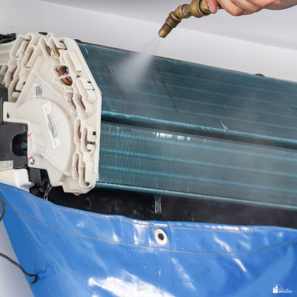 Cleaning air conditioner coils with water spray, highlighting a common DIY maintenance task that may cause damage without proper care.