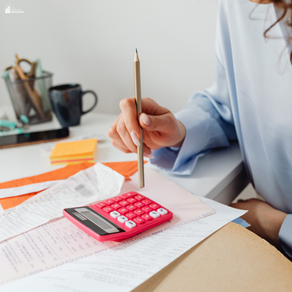 Person reviewing household bills with a calculator while managing expenses related to high electricity costs.
