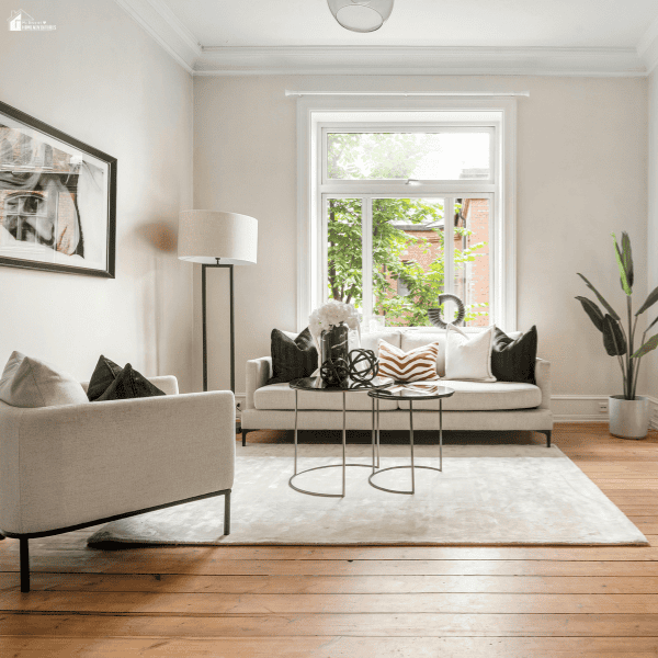 Bright and functional living room with neutral seating, layered lighting, a large area rug, and an open layout designed for everyday comfort and conversation.