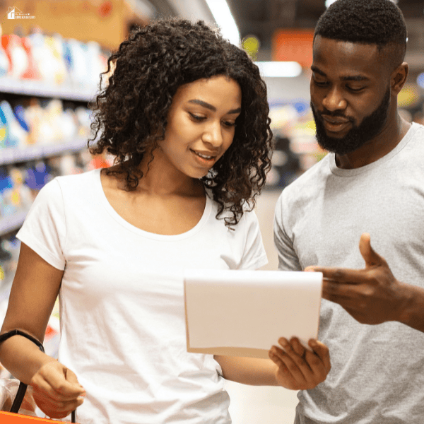 Couple checking a grocery list together in a supermarket while planning budget-friendly meals and smart grocery shopping.