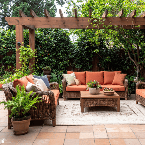 Comfortable backyard seating area with wicker furniture, outdoor cushions, and greenery designed for relaxing gatherings.