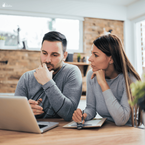 Couple reviewing finances and business plans together on a laptop at home while budgeting for a new venture.