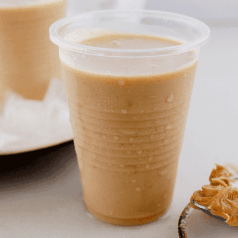 Creamy peanut butter limber in a chilled plastic cup with peanut butter in the background.