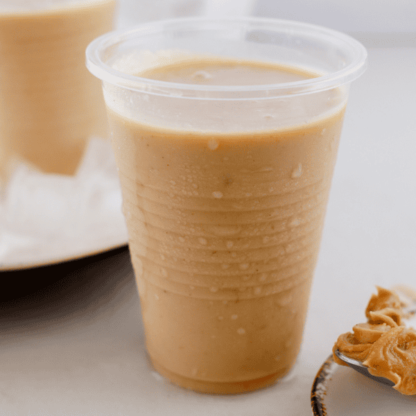 Creamy peanut butter limber in a chilled plastic cup with peanut butter in the background.