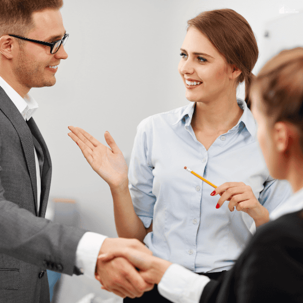 Renters and property professionals shaking hands during a housing agreement discussion focused on lowering rental costs.