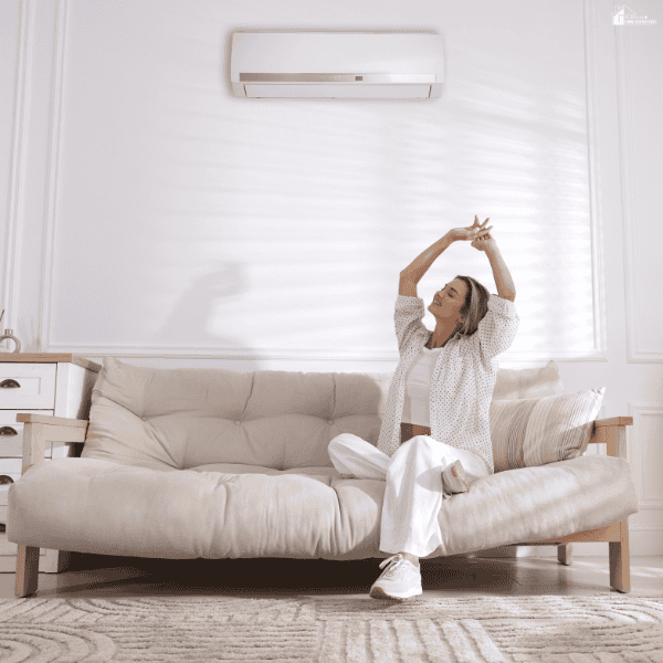 Bright living room with a cozy sofa, soft natural light, and a wall-mounted air conditioner creating a calm and comfortable home environment for easier daily living.