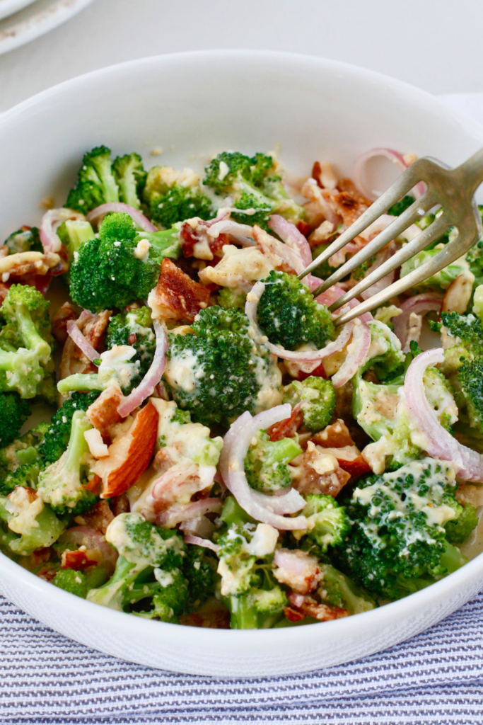 Creamy broccoli salad with bacon, red onion, almonds, and parmesan cheese served as an easy cold summer side dish.