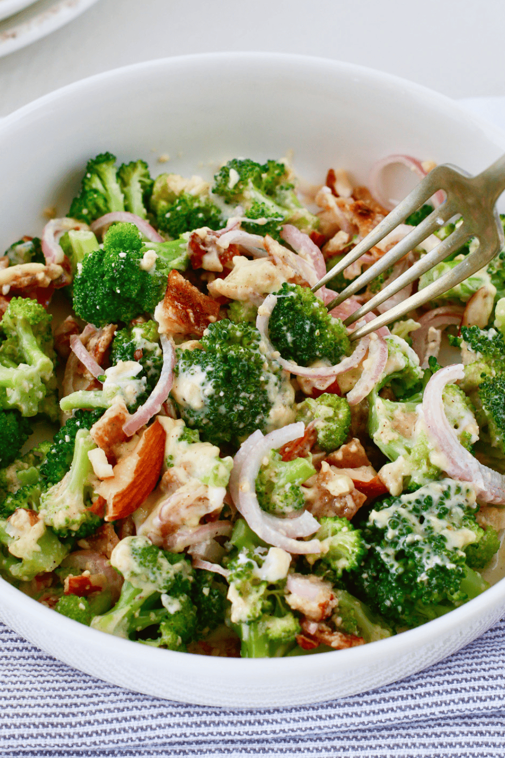 Creamy broccoli salad with bacon, red onion, almonds, and parmesan cheese served as an easy cold summer side dish.