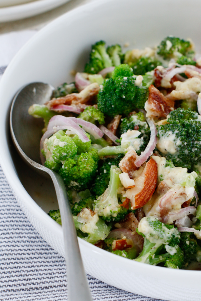 Cold broccoli salad with bacon, almonds, parmesan cheese, and red onion in a creamy dressing served as an easy summer side dish.