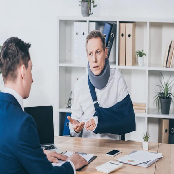 Injured man with arm sling and neck brace speaking with a professional about financial survival after losing income from an injury.