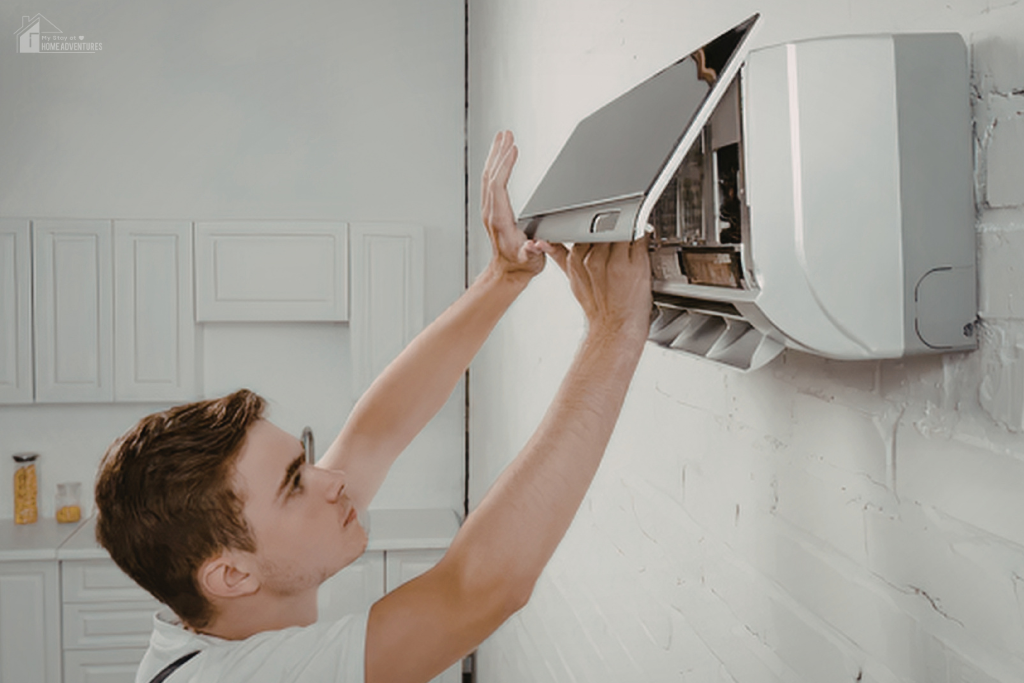 Man opening wall-mounted HVAC unit to check inside, showing maintenance that can help reduce high energy bills and improve efficiency