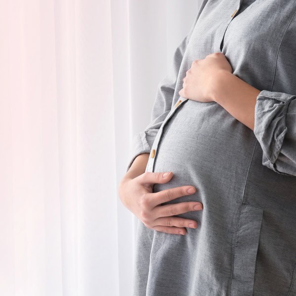Pregnant woman holding her baby bump while planning for financial protection and life insurance as a new parent.