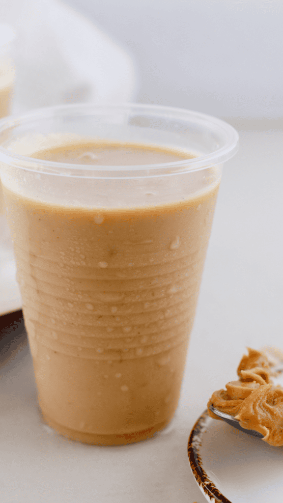 Creamy peanut butter limber in a chilled plastic cup with peanut butter in the background.