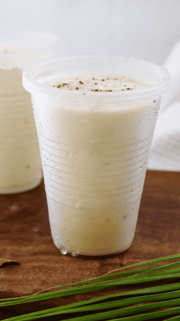 Creamy Puerto Rican tres leches limber in a chilled plastic cup with cinnamon sprinkled on top.