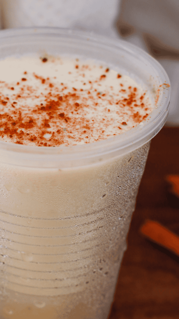 Close-up of homemade tres leches limber with cinnamon topping and frosty texture in a plastic cup.