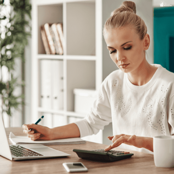 Person using a calculator and laptop to track expenses, highlighting money-saving strategies for groceries, transportation, and family activities.