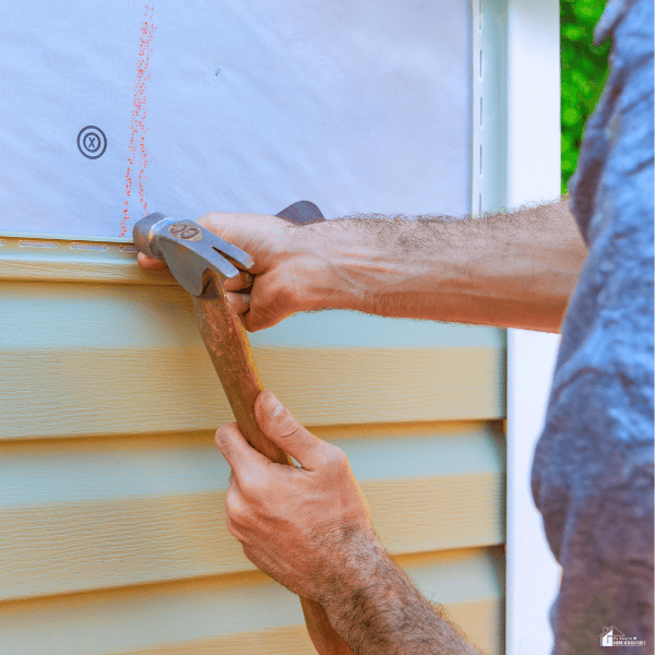 Homeowner installing exterior siding as part of a property improvement project that requires careful repair budgeting.