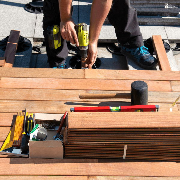 Patio builder installing decking boards and structural components for a custom outdoor living area designed for long-term durability.