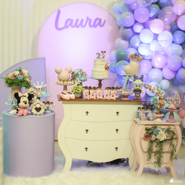 Pastel-themed celebration display with balloons, desserts, and decorative accents arranged against a custom event backdrop.