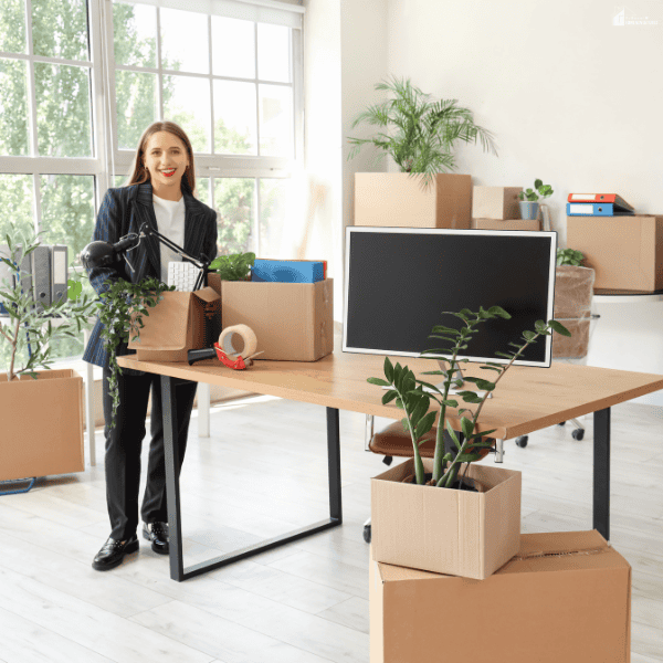 Person organizing packed boxes and office essentials during a moving process to a new workspace.