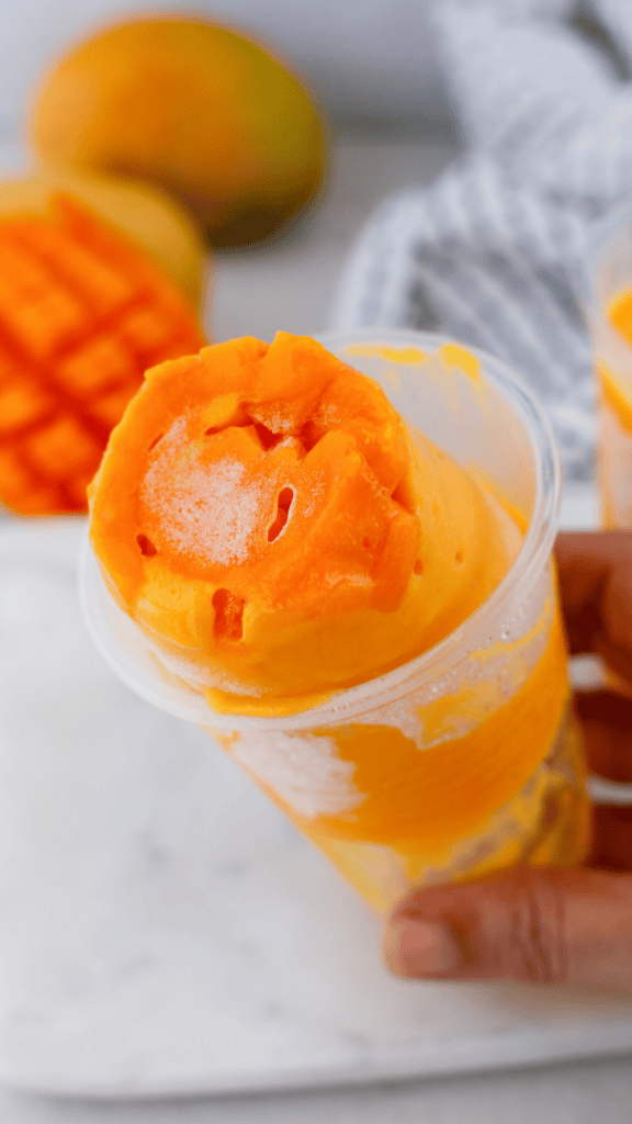 Limber de mango frozen dessert with fresh mango pieces served in a plastic cup for a classic Puerto Rican treat.