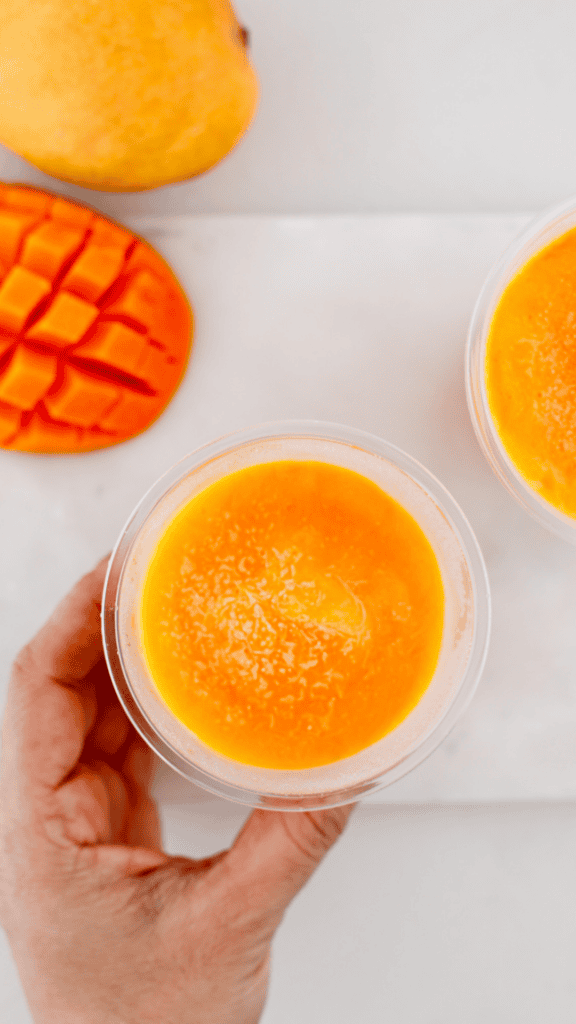 Homemade limber de mango frozen in individual cups and served alongside ripe mangoes.