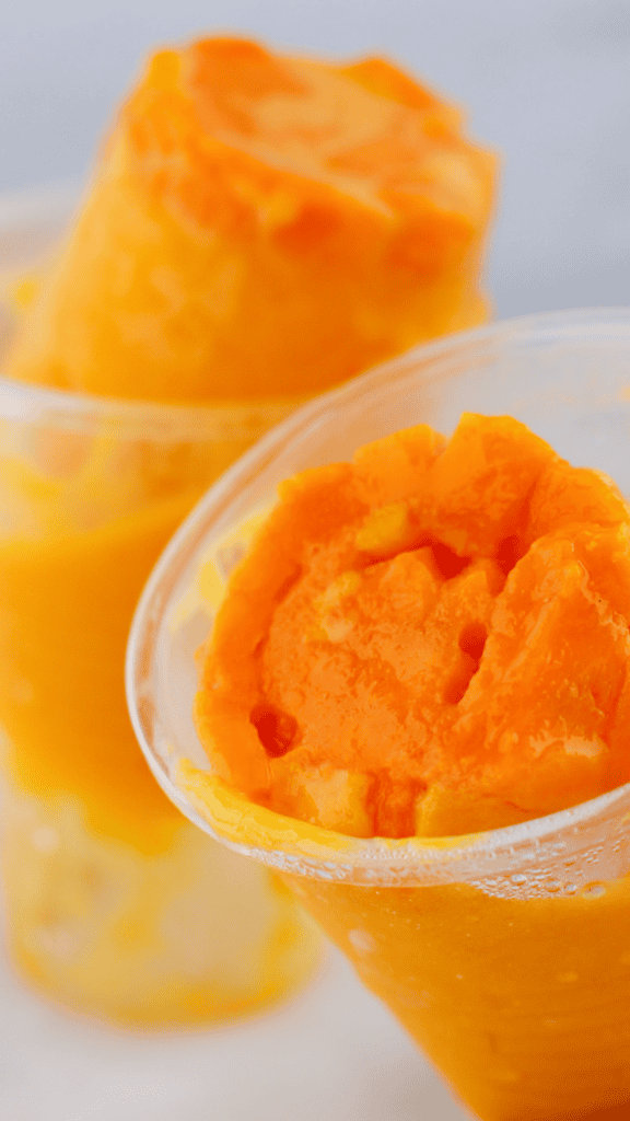 Close-up of limber de mango showing creamy frozen mango layers and chunks of fresh fruit.