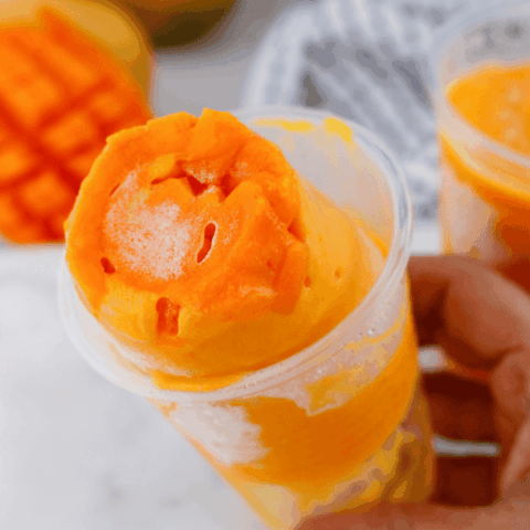 Limber de mango frozen dessert with fresh mango pieces served in a plastic cup for a classic Puerto Rican treat.