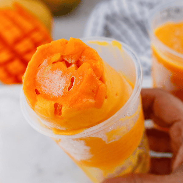 Limber de mango frozen dessert with fresh mango pieces served in a plastic cup for a classic Puerto Rican treat.